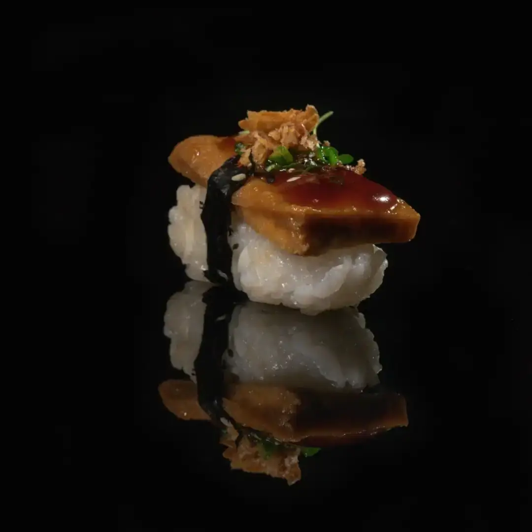 Single pieces of nigiri mirrored on black glass