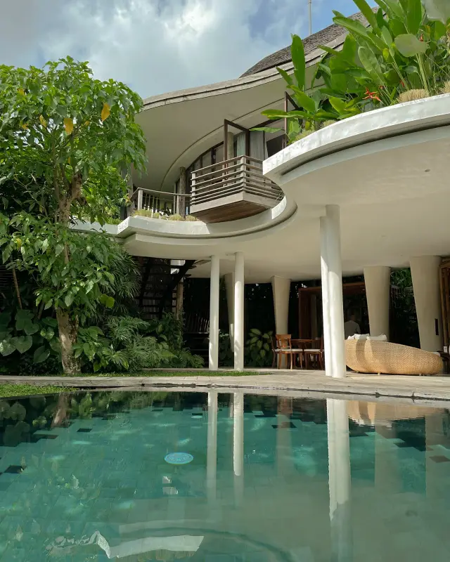 The villa reflected in the pool, jungle rising behind it — Mango Ubud