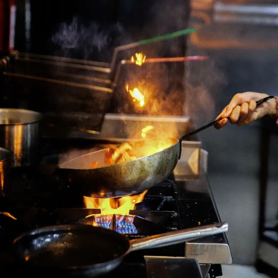 Flames leaping from a wok in the open kitchen
