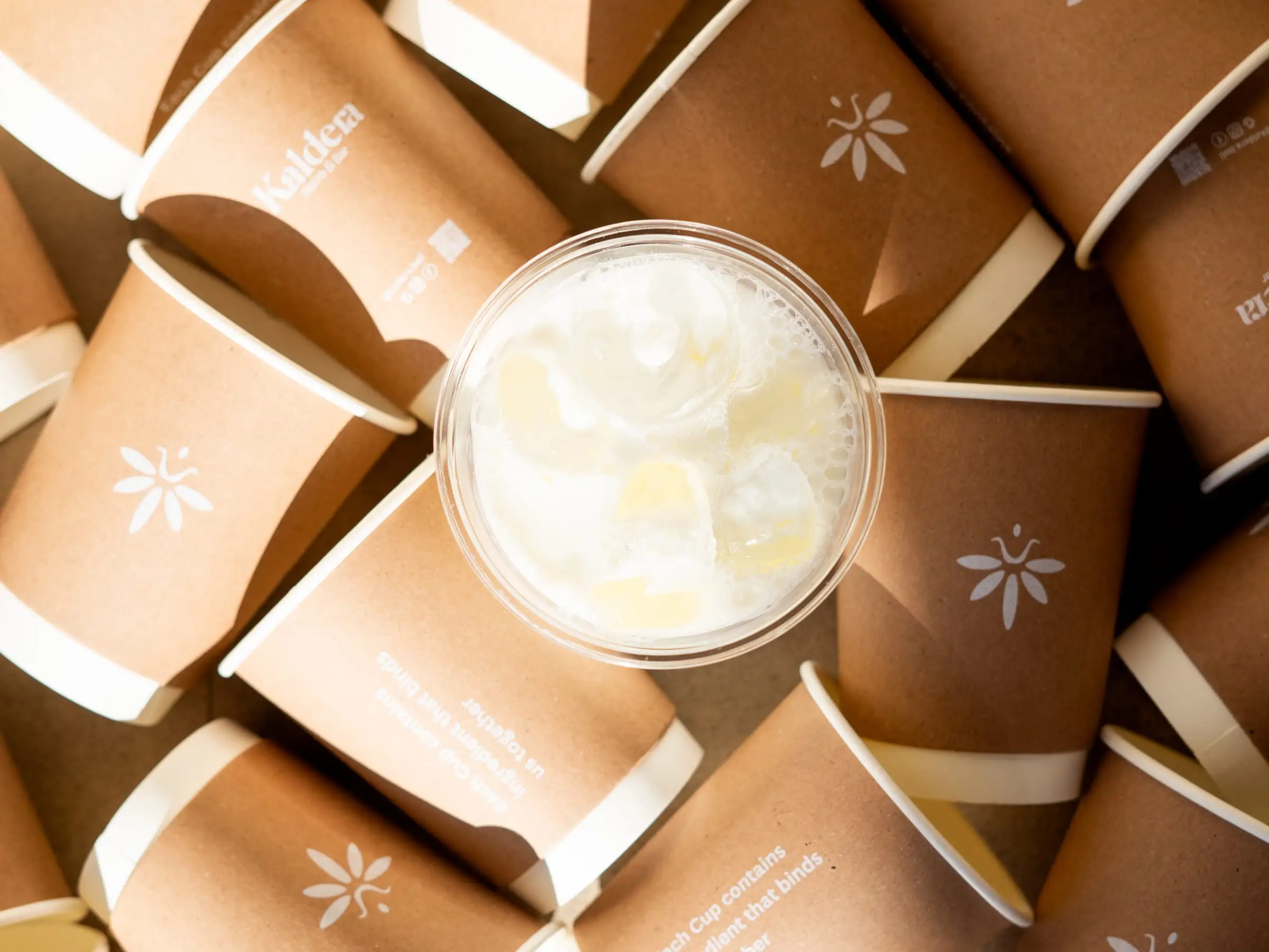 Iced latte surrounded by branded paper cups, shot from above