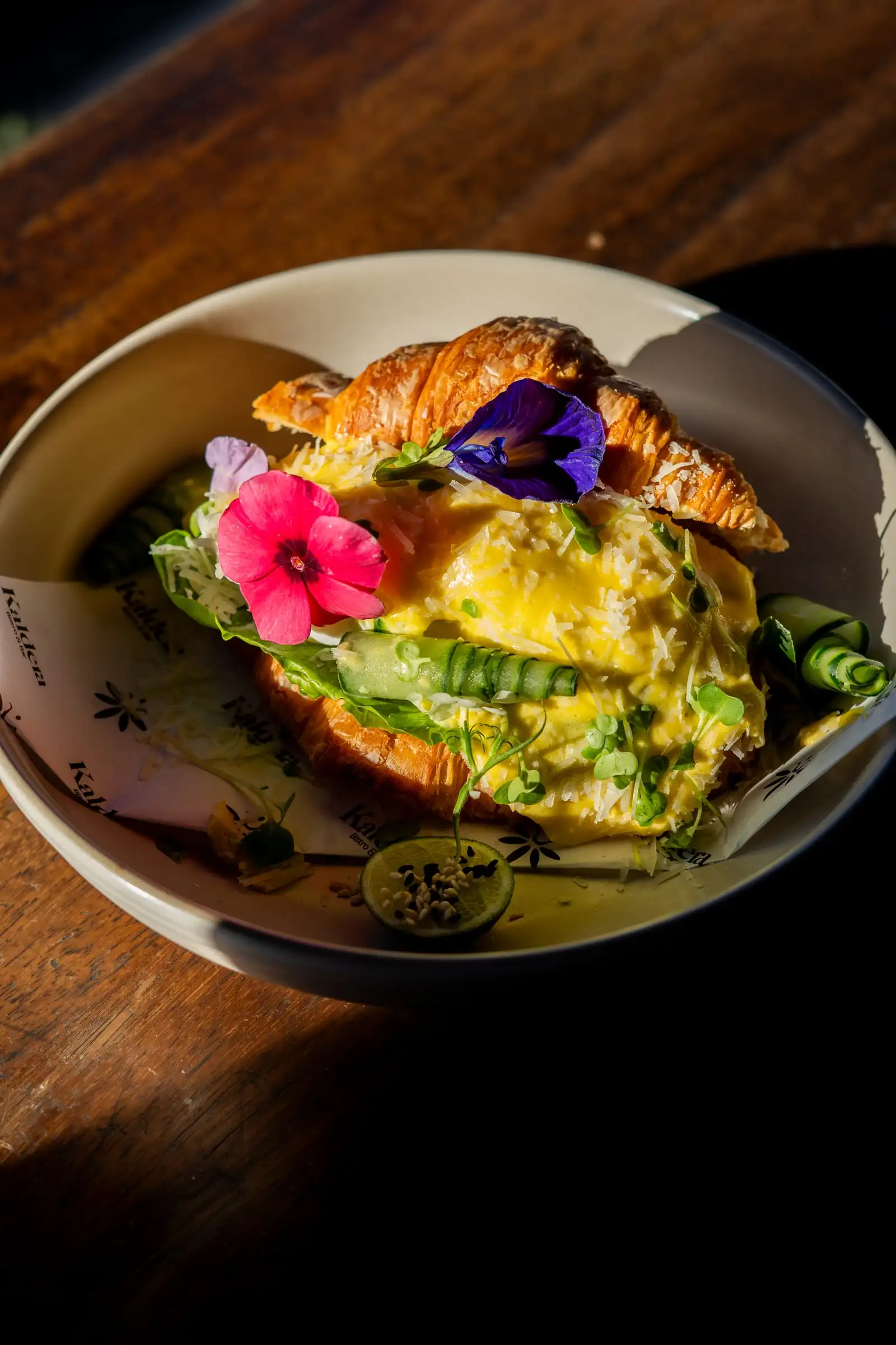 Croissant isi telur dan alpukat berhias bunga ungu