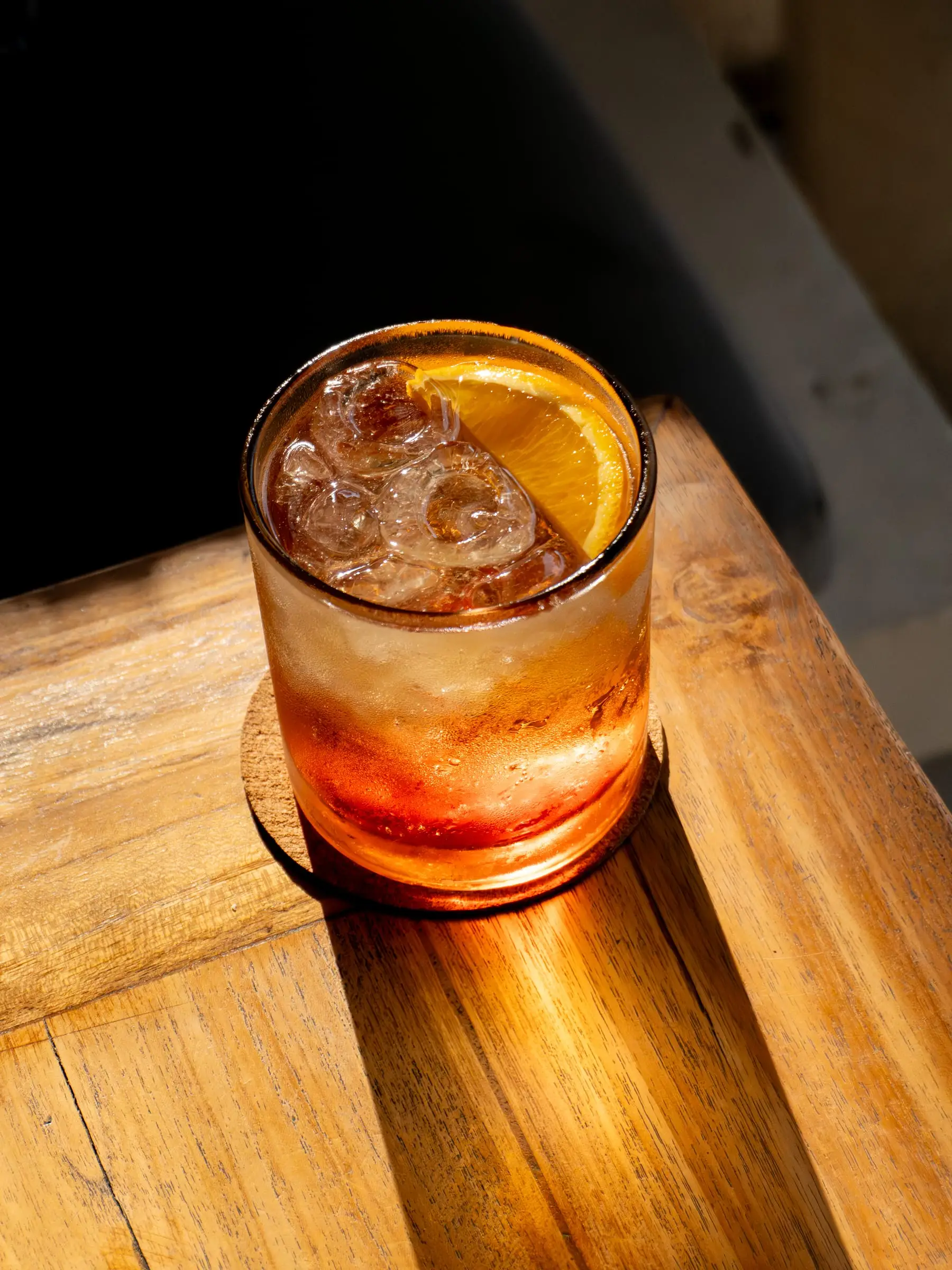 Cocktail in a short glass with ice and orange in late-afternoon light