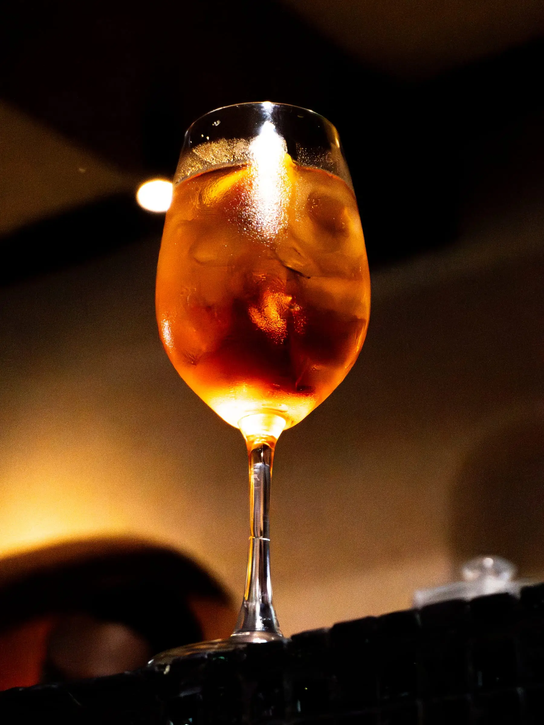 Orange spritz in a wine glass against a dark background