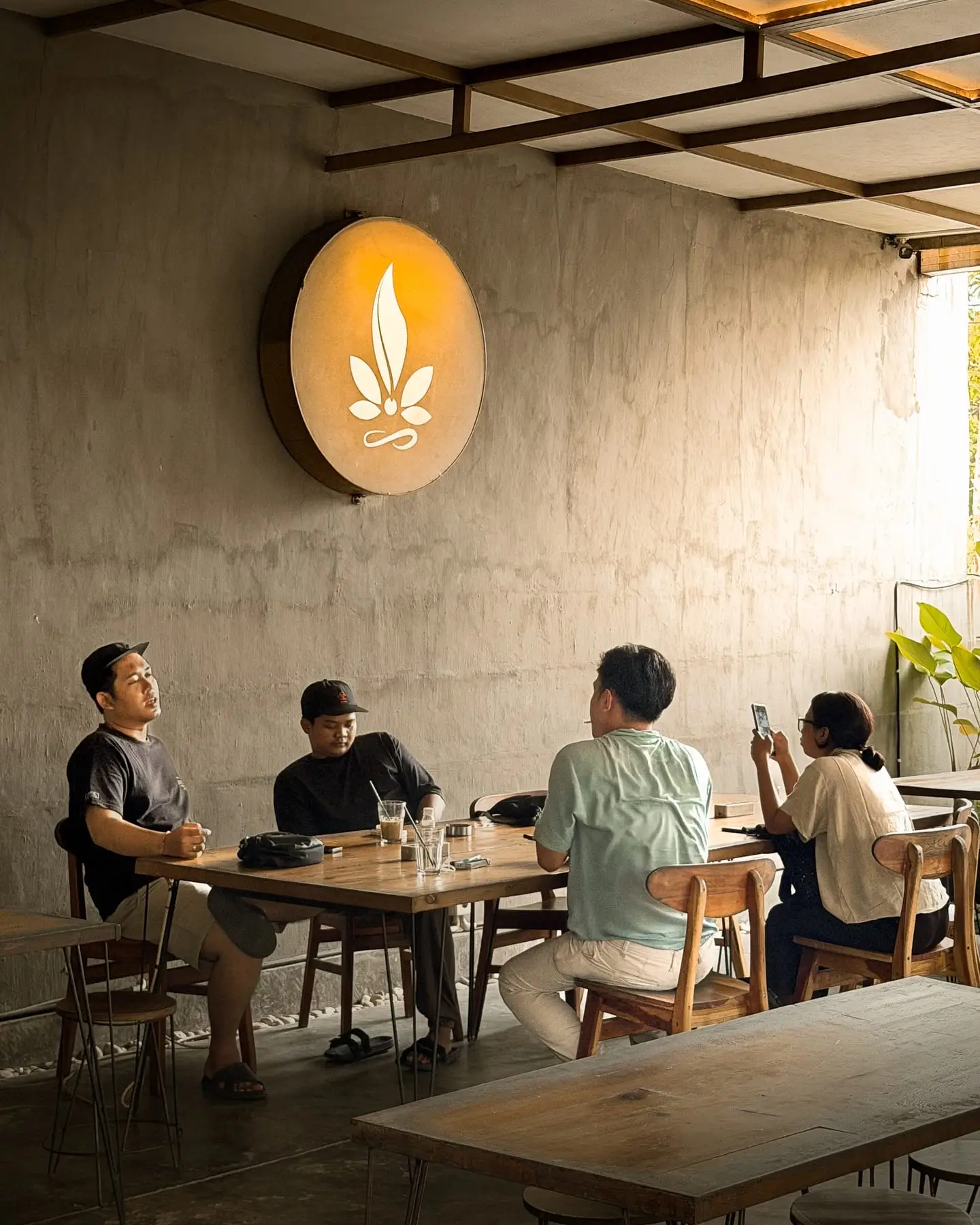 Suasana kafe dengan tamu duduk di dekat logo bercahaya